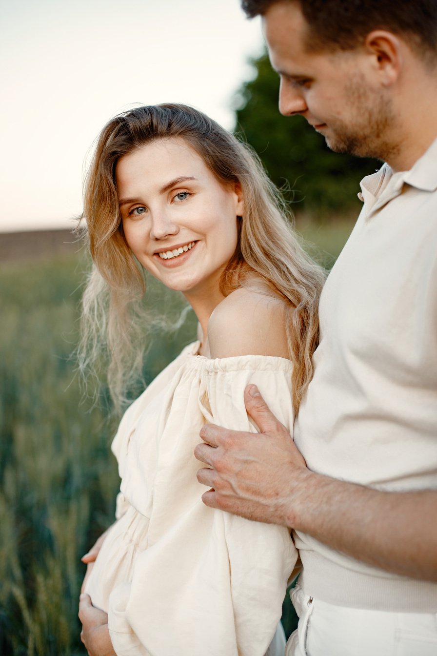 Pregnant Woman with Husband Standing on the Field