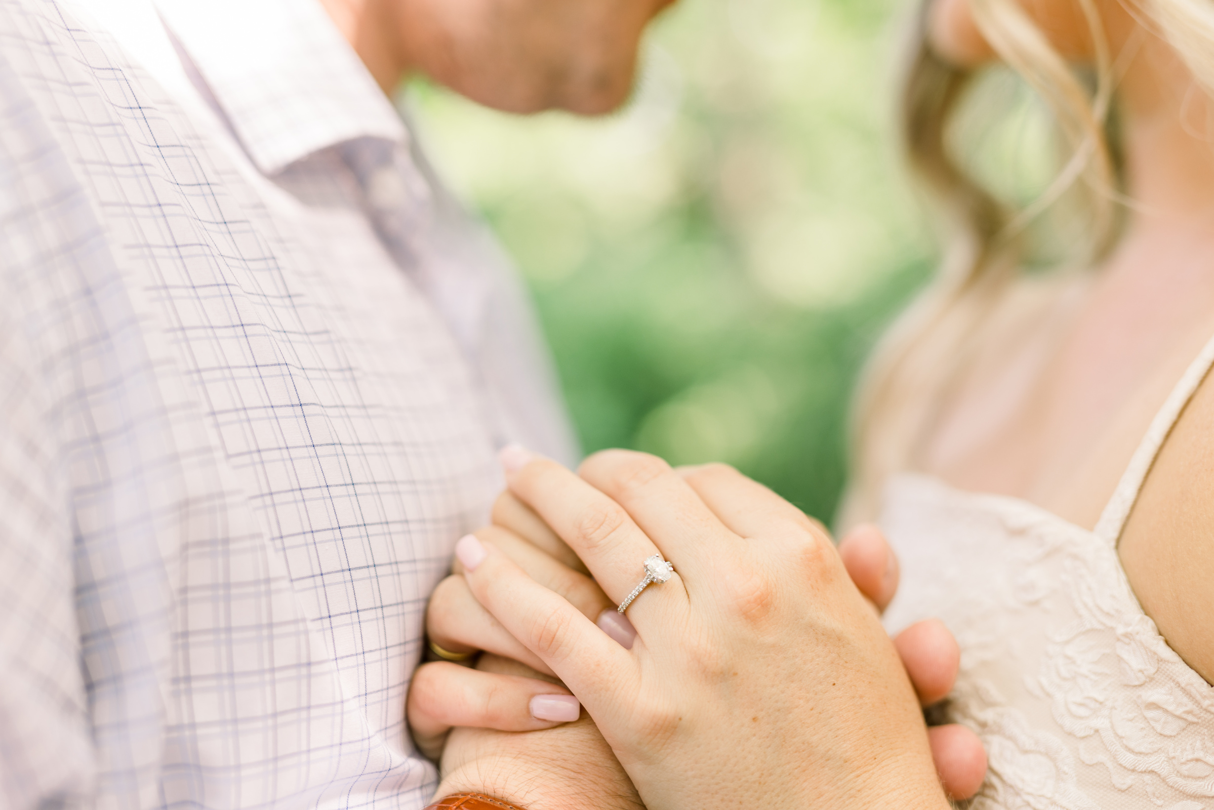 A man and woman have hands held together during engagement photo